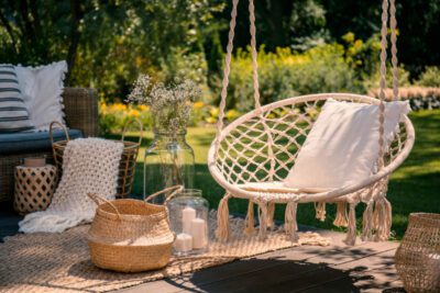 A beige string swing with a pillow on a patio