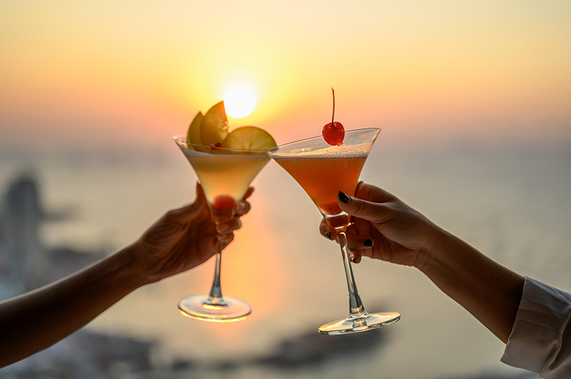 Couple enjoying of Cheers glass of cocktail in a restaurant at sunset view sea. Cocktail, Couple, Honeymoon, Dinner, Wine, Romantic concept.