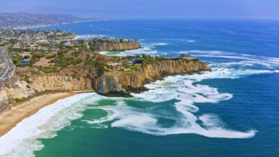 Aerial view of houses on rocky cliff along coastline, Laguna Beach, Blue Lagoon, California, USA.